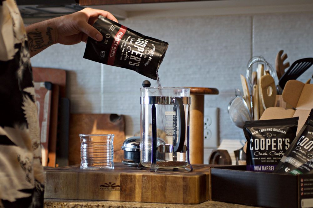A kitchen scene where Cooper's Craft Coffee is being poured into a French press showing the coffee flavor profile