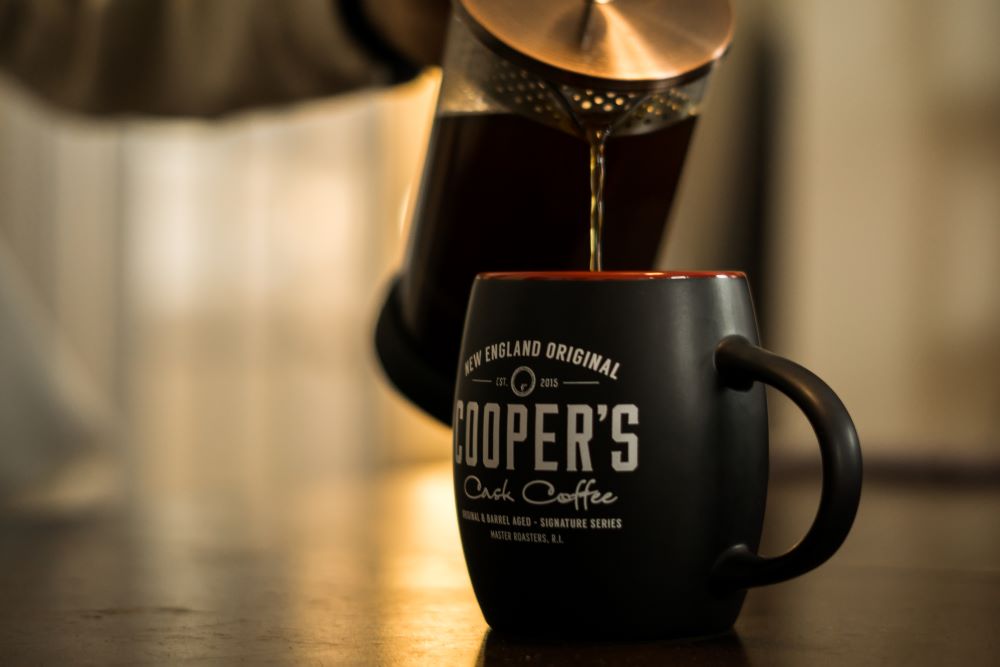 A french press brewer pouring delicious Cooper's Craft bourbon coffee into a cup for father's day gift ideas