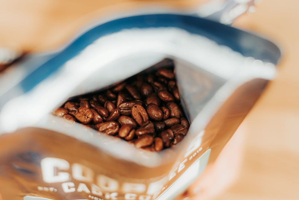 a close up of coffee beans in a bag of cooper's cask coffee as one of the ways to keep fresh coffee beans stored