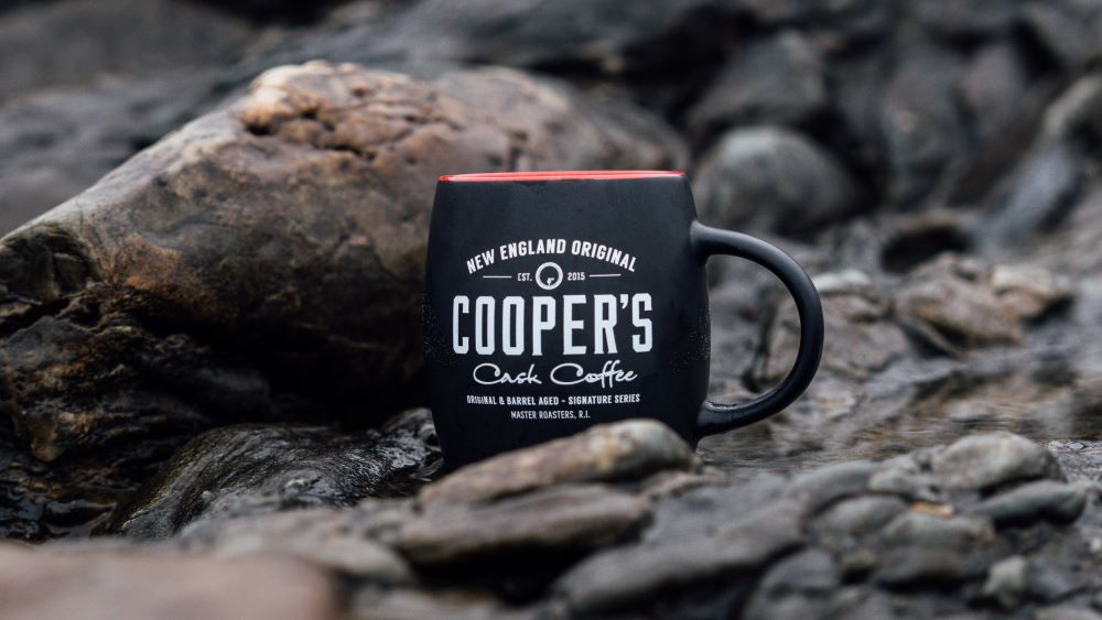 a cooper's cask coffee mug in the outdoors as part of a beautiful shot for whole bean vs ground coffee