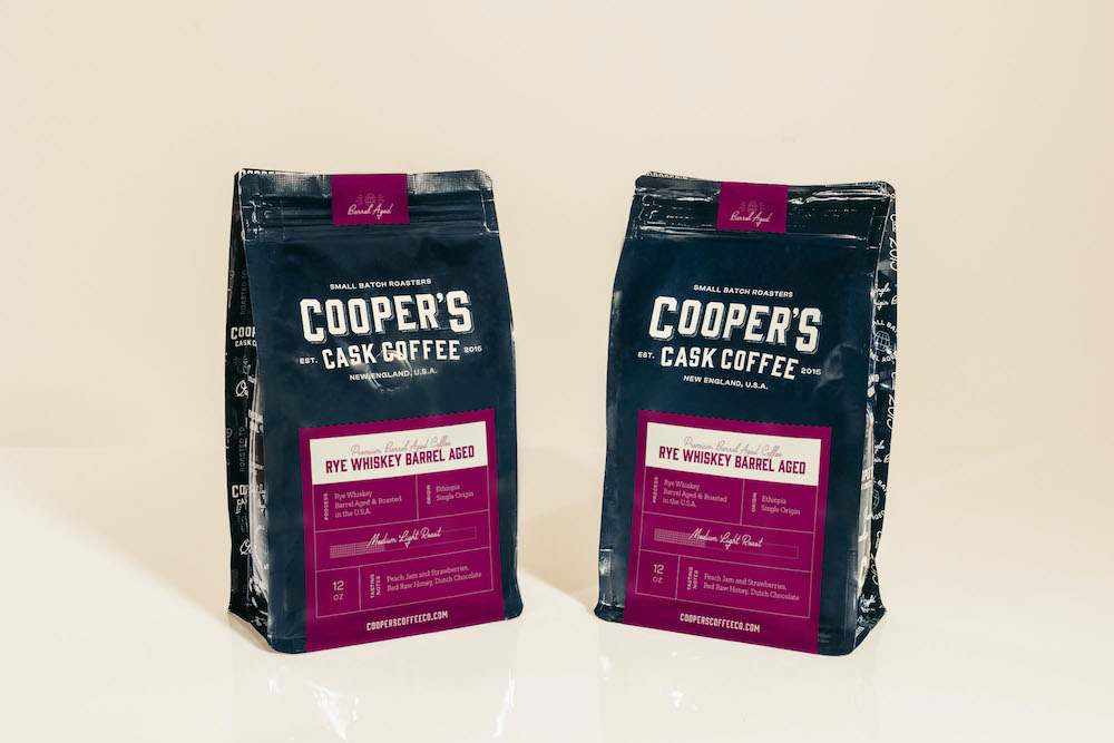 two bags of rye whiskey barrel aged coffee agains beige background as product of whiskey and coffee flavor enhancement