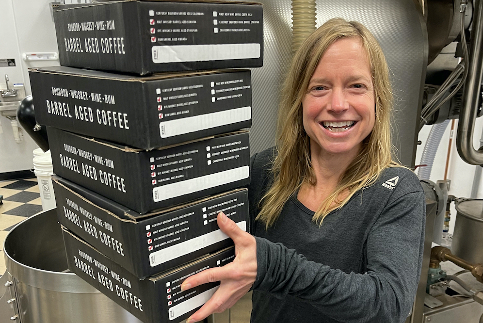 a cooper's cask coffee worker holding a stack of coffee boxes showing hard work of wholesale coffee suppliers